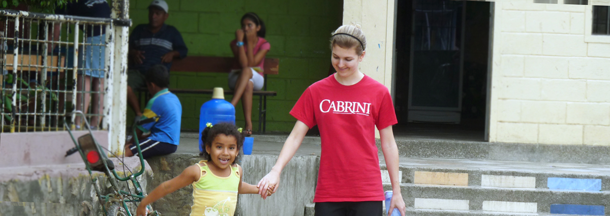 A Cabrini student with a local child in Ecuador during a service trip